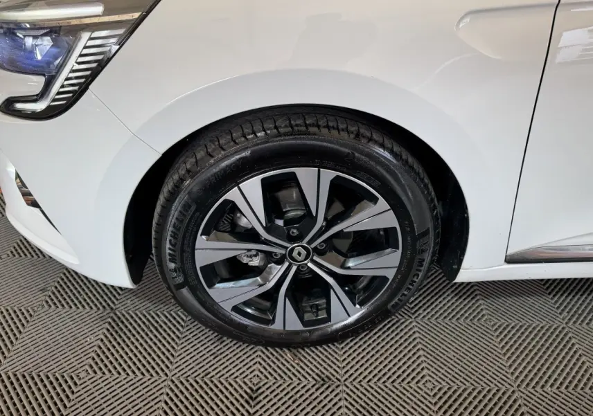 Gros plan sur la roue avant gauche de la Renault Clio blanche avec jante alliage au design moderne et logo Renault central.