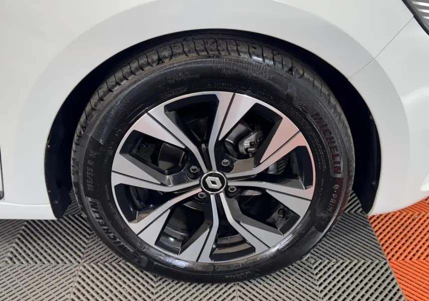 Gros plan sur la roue avant gauche d’une Renault Clio blanche, avec jante alliage bicolore et pneu Michelin.