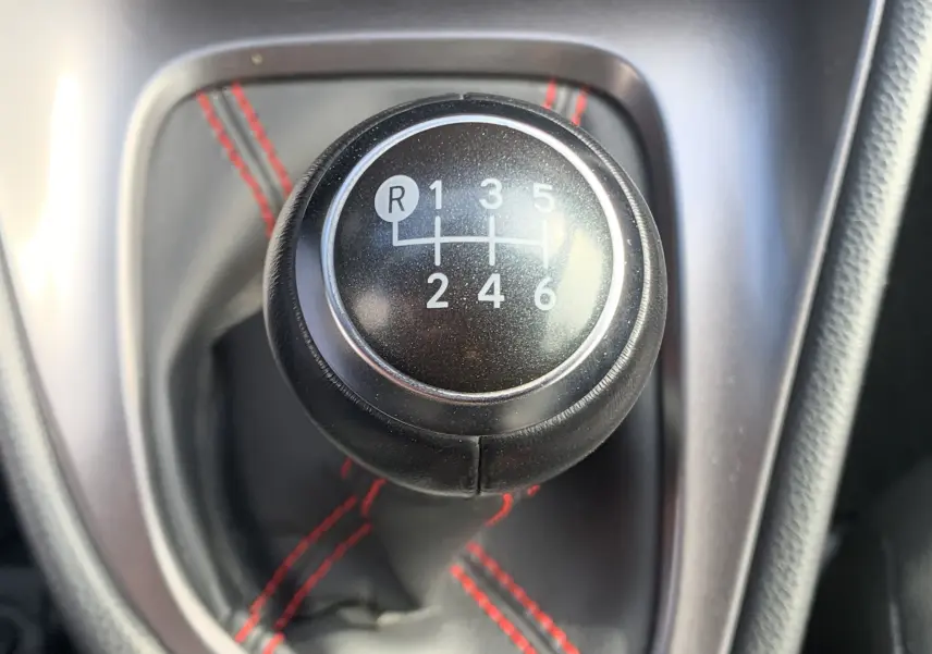 Le levier de vitesses manuel noir avec surpiqûres rouges dans une Toyota Yaris blanche 2021.