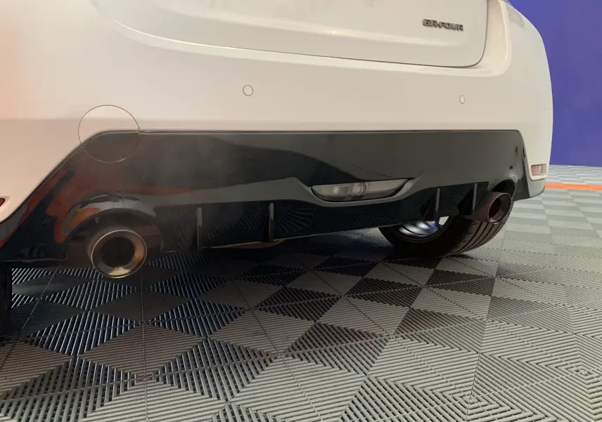 Gros plan sur le bas arrière blanc métal de la Toyota Yaris 1.6 VVT-I 261 Premium GR avec double sortie d’échappement et diffuseur noir.
