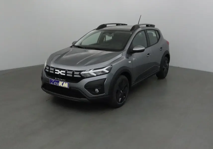 Vue 3/4 avant d'une Dacia Sandero Stepway 2025 gris schiste avec calandre noire et jantes foncées.
