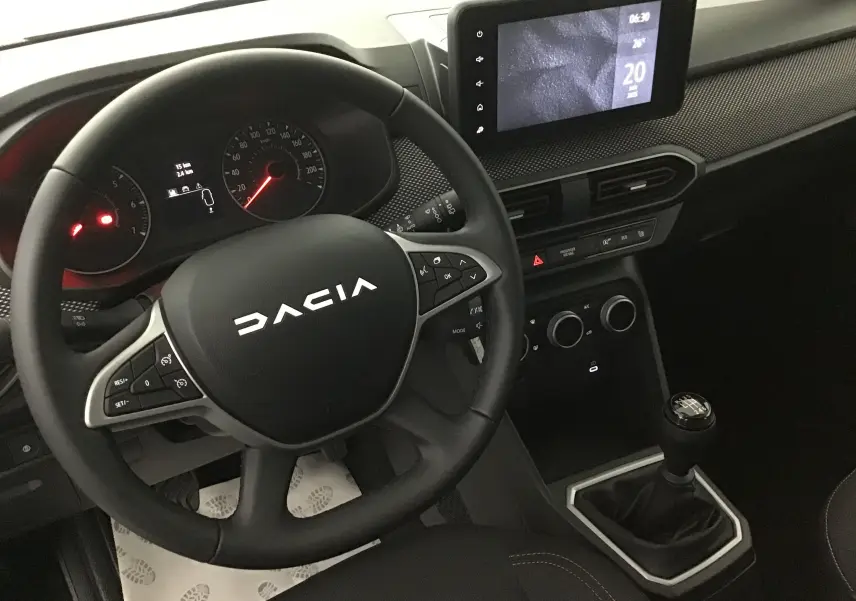 Vue intérieure du tableau de bord et volant DACIA Sandero Stepway 2025 avec écran tactile et levier de vitesse manuel.