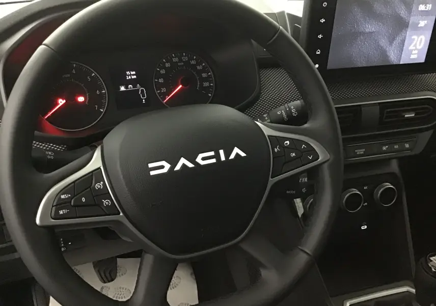 Vue rapprochée du volant noir de la Dacia Sandero Stepway 2025 avec tableau de bord et écran tactile.