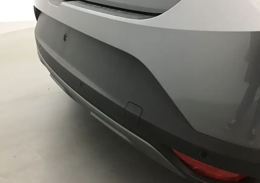 Gros plan sur le pare-chocs arrière gris schiste de la Dacia Sandero Stepway 2025 avec feu arrière et capteurs de recul.