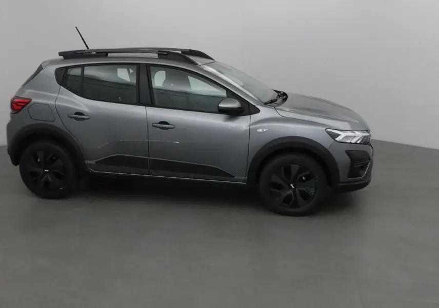 Profil côté gauche d'une Dacia Sandero Stepway gris schiste 2025 avec barres de toit et jantes noires.