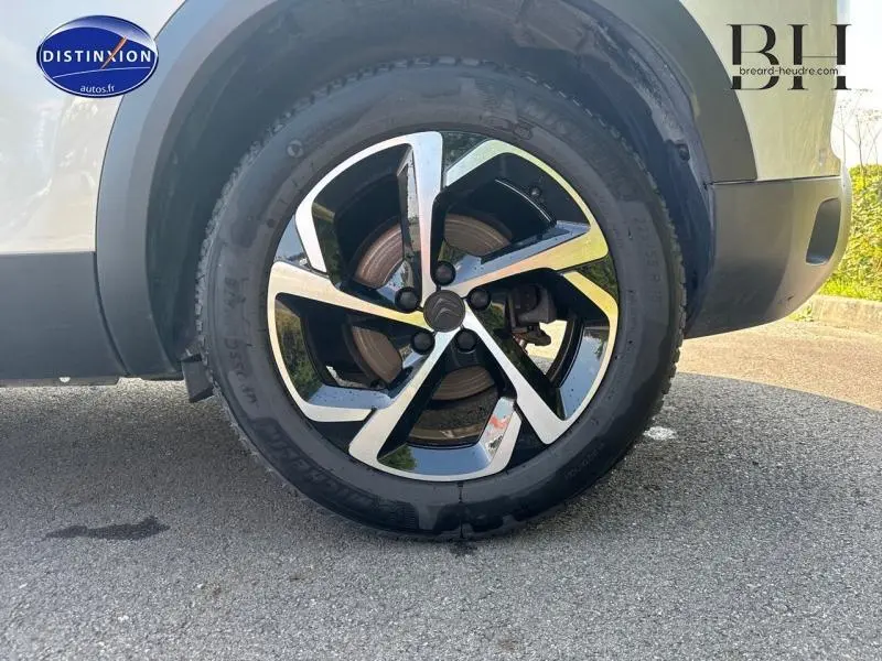 Gros plan sur la roue avant droite du Citroën C5 Aircross blanc nacré avec jante alliage bicolore moderne.