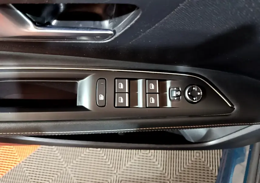Vue rapprochée des commandes de lève-vitres et rétroviseurs sur la porte côté gauche d’un Peugeot 3008 bleu.