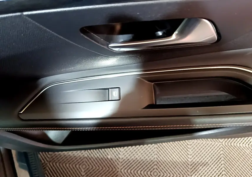 Gros plan sur la poignée intérieure et le bouton de lève-vitre côté gauche d’une Peugeot 3008 GT bleu.