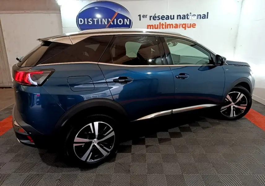 Vue côté droit du Peugeot 3008 PureTech 130 GT bleu, avec jantes alliage et toit noir contrasté en intérieur showroom.