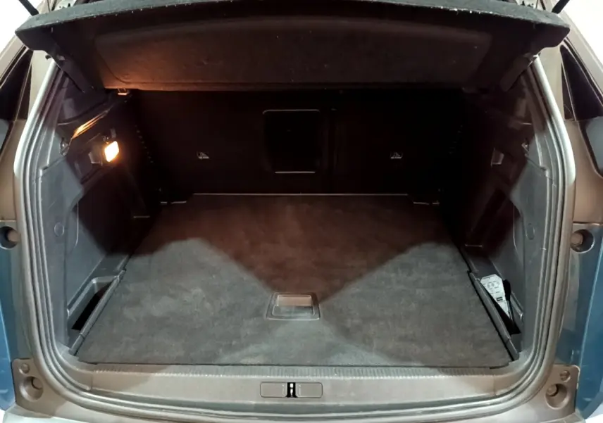 Coffre ouvert vu de l'arrière du Peugeot 3008 PureTech 130 bleu, espace de rangement spacieux et éclairé.