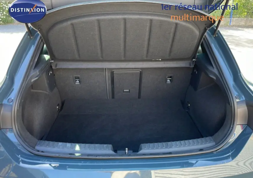 Coffre ouvert vu de l'arrière d'une CUPRA Leon 1.5 eTSI 150CH DSG bleu Fjord, intérieur du coffre en tissu noir.
