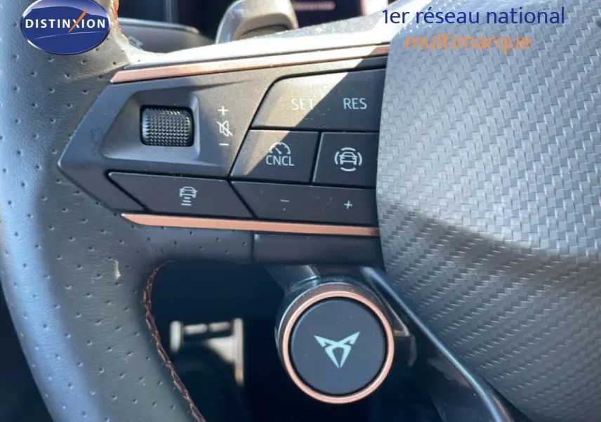 Gros plan sur le volant en cuir perforé avec commandes intégrées et logo CUPRA, intérieur noir du Leon 1.5 eTSI bleu Fjord.