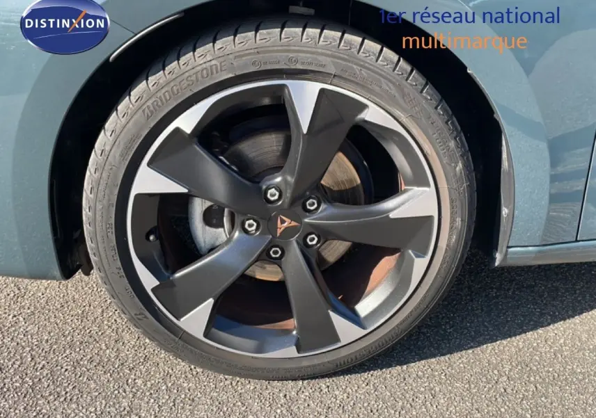 Gros plan sur la roue avant gauche de la CUPRA Leon 1.5 eTSI 150CH DSG en bleu Fjord avec jante alliage noire et grise.