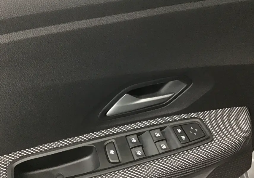 Gros plan sur la commande des vitres électriques et la poignée intérieure côté gauche d'une Dacia Sandero Stepway 2025.