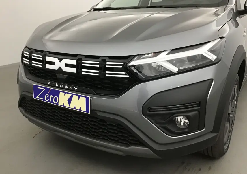 Vue de face droite d'une Dacia Sandero Stepway gris schiste avec calandre noire et éclairage LED distinctif.