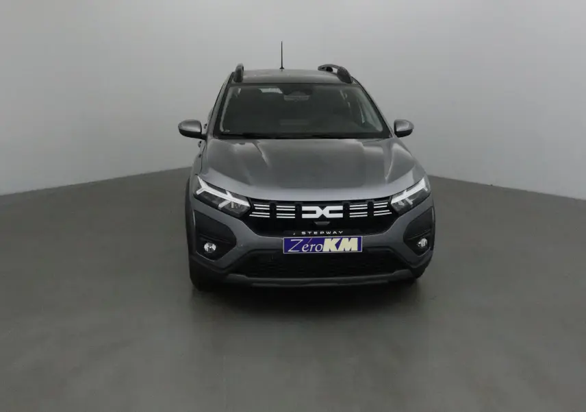 Vue frontale d'une Dacia Sandero Stepway gris schiste avec calandre noire et phares LED distinctifs.