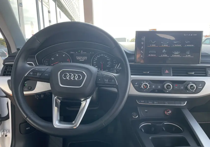 Intérieur de l'Audi A4 Avant blanc 2022, vue centrée sur le volant et le tableau de bord avec écran tactile allumé.