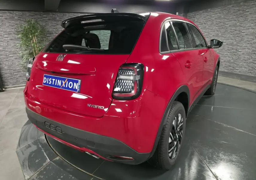 Vue 3/4 arrière droite d'une FIAT 600 rouge hybride 2024 avec feux arrière LED et jantes bicolores.