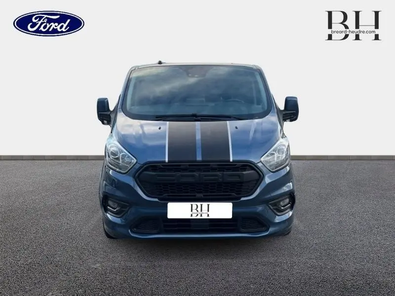 Vue frontale d'un Ford Transit Custom Fourgon bleu azur métallisé avec bandes noires sur le capot.