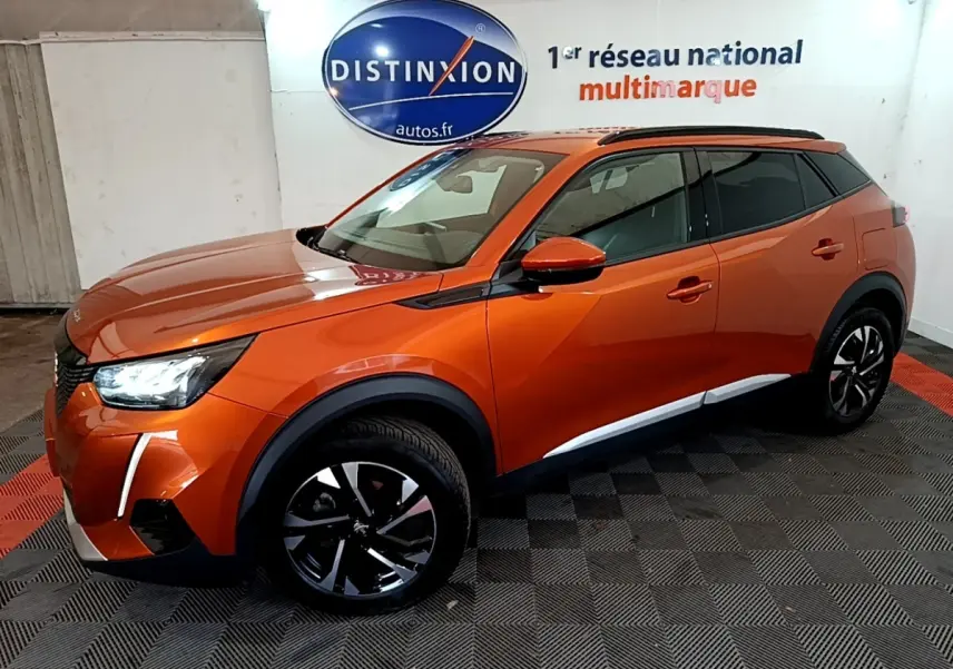 Peugeot 2008 orange vue 3/4 avant droit dans un showroom avec jantes noires et toit noir.
