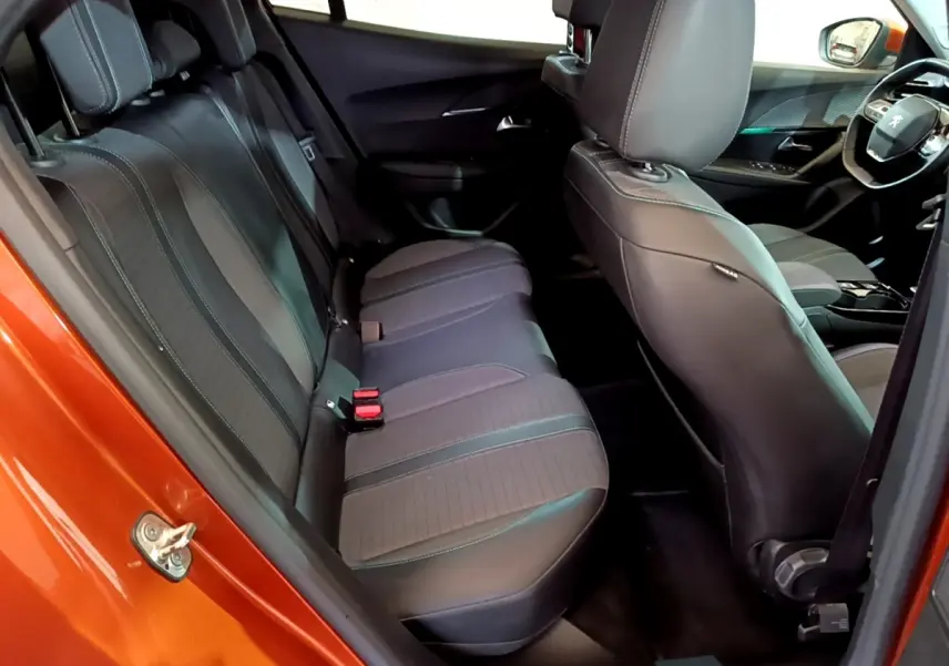 Vue intérieure côté arrière gauche du Peugeot 2008 orange, montrant la banquette arrière et les sièges avant en tissu noir.