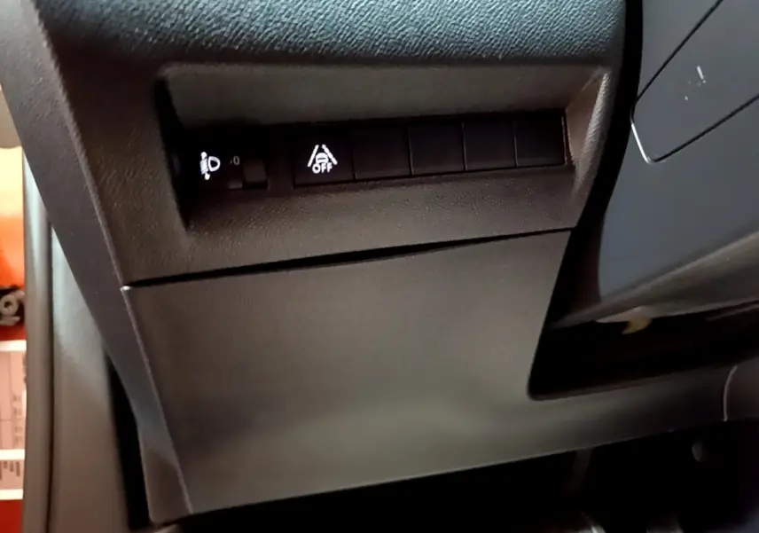 Détail du tableau de bord côté gauche avec commandes de réglage des phares et assistance au maintien de voie, intérieur noir.