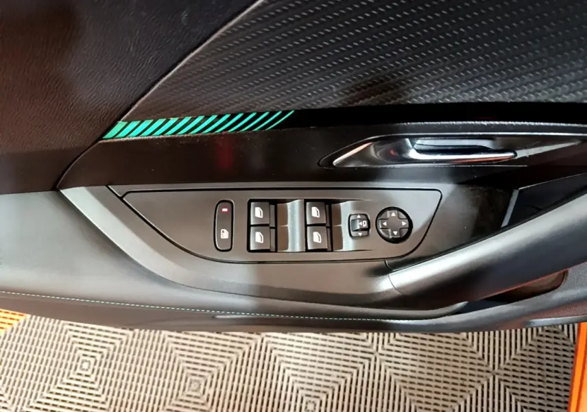 Détail de la porte côté gauche de la Peugeot 2008 orange, avec commandes des vitres et poignée chromée.