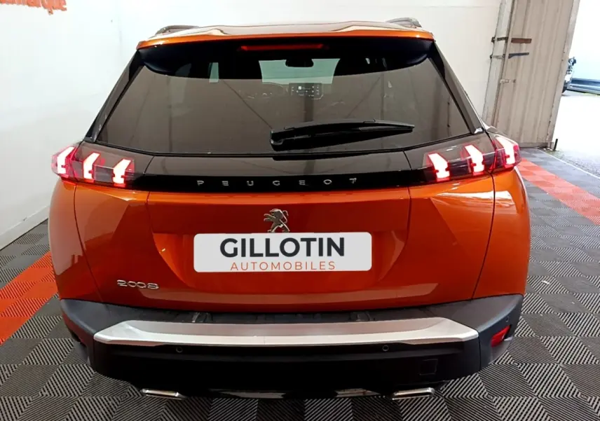 Vue arrière d'un Peugeot 2008 orange avec feux arrière LED caractéristiques et logo central sur hayon noir.