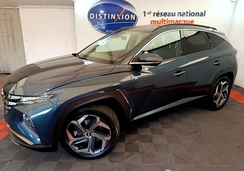 Vue 3/4 avant droit du Hyundai Tucson bleu 2023 avec jantes alliage et toit noir dans un showroom.