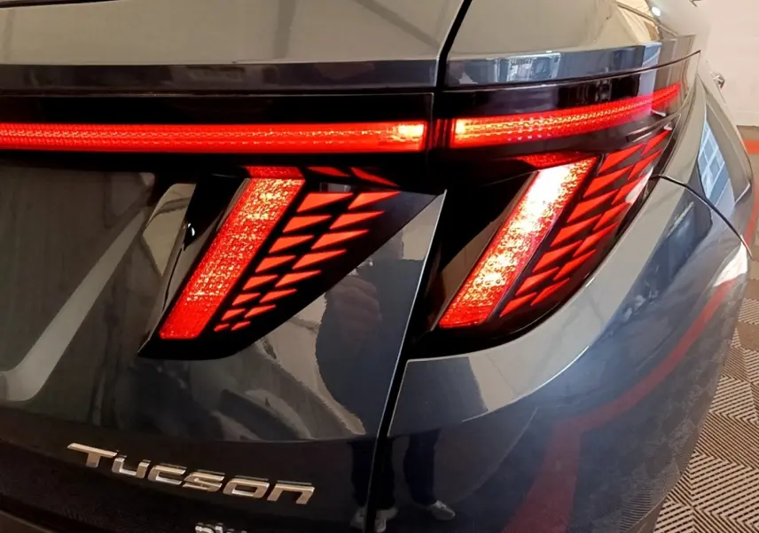 Gros plan sur le feu arrière droit allumé du Hyundai Tucson bleu 2023 avec logo Tucson visible sur le hayon.
