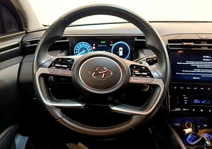 Vue intérieure centrée sur le volant cuir du Hyundai Tucson 2023 avec tableau de bord numérique et écran tactile central.
