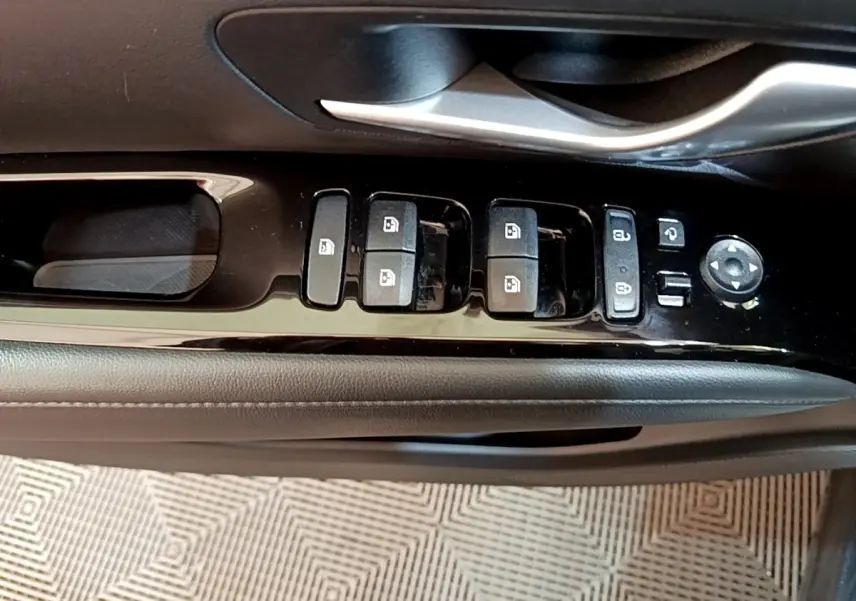 Gros plan sur la commande des vitres et rétroviseurs côté conducteur du Hyundai Tucson bleu 2023.