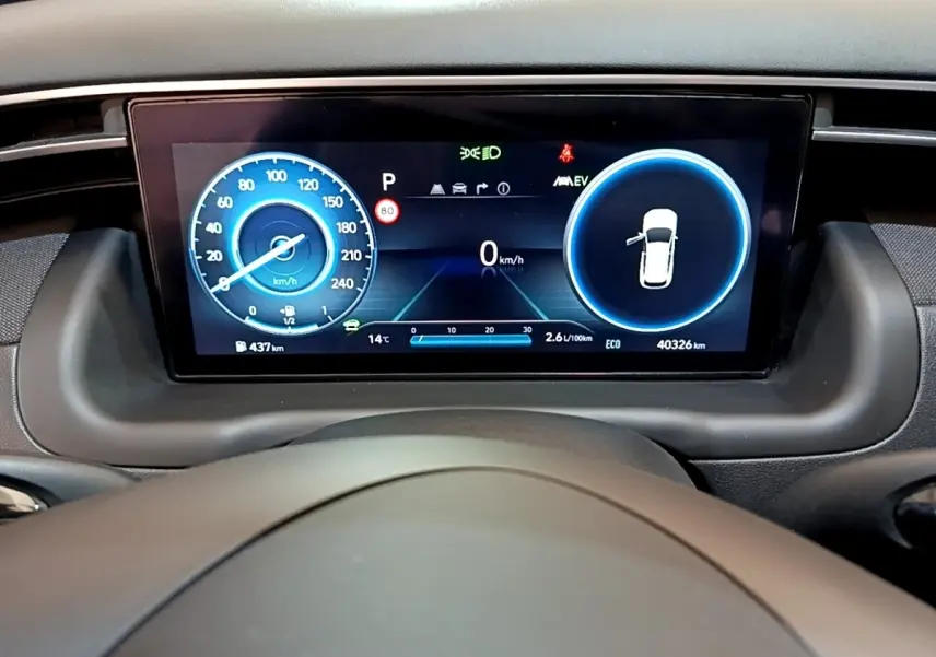 Tableau de bord numérique du Hyundai Tucson 2023, affichage couleur avec vitesse et indicateurs, vue de face depuis le volant.