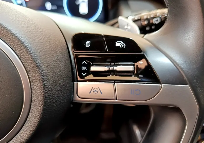 Gros plan sur les commandes multifonctions côté droit du volant cuir du Hyundai Tucson bleu 2023 hybride rechargeable.
