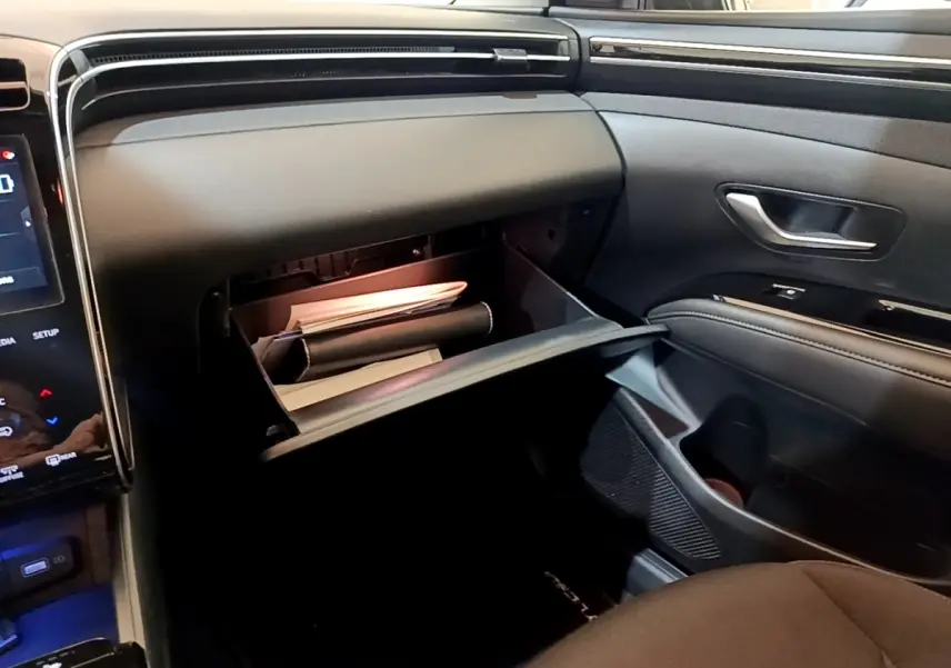 Vue intérieure côté passager du Hyundai Tucson 2023, boîte à gants ouverte avec documents visibles.