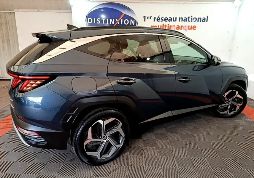 Vue 3/4 arrière droite du Hyundai Tucson bleu 2023 avec feux LED distinctifs et jantes alliage modernes.