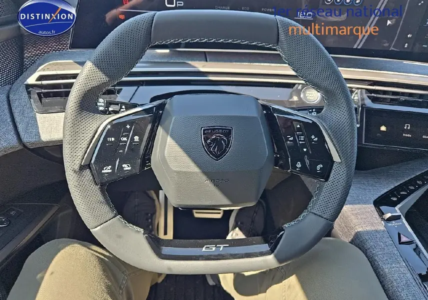 Vue rapprochée du volant cuir perforé gris titane du Peugeot 5008 Hybrid 145 GT avec commandes multifonctions intégrées.