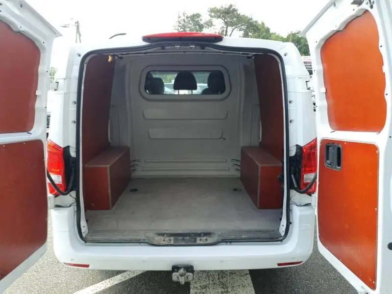 Vue arrière ouverte du Mercedes Vito Fourgon blanc avec intérieur de chargement protégé par panneaux en bois marron.
