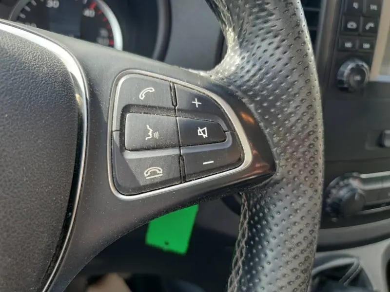 Gros plan sur les commandes audio et téléphone sur le volant en cuir perforé du Mercedes Vito Fourgon blanc de 2017.
