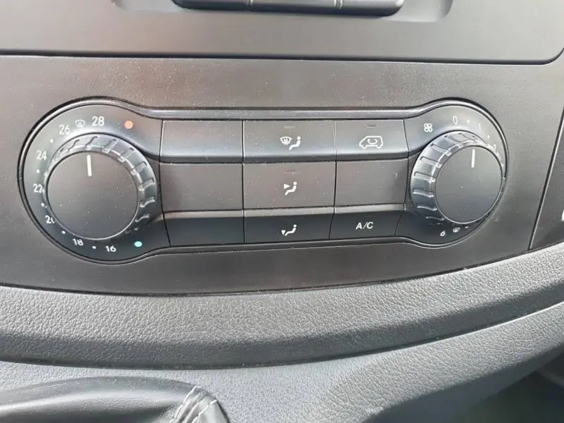 Gros plan sur les commandes de climatisation noires du Mercedes Vito Fourgon blanc, avec réglages de température et ventilation.
