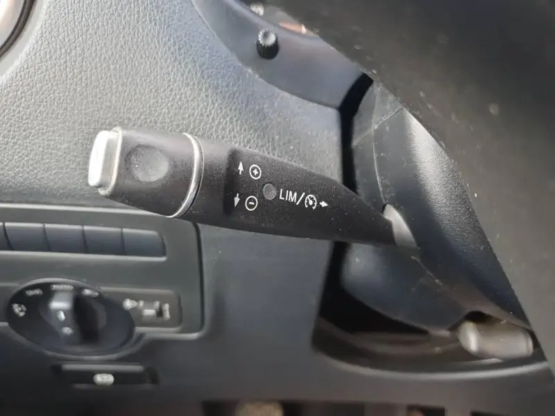 Le levier de régulateur de vitesse noir du Mercedes Vito Fourgon blanc, vue rapprochée côté gauche du volant.