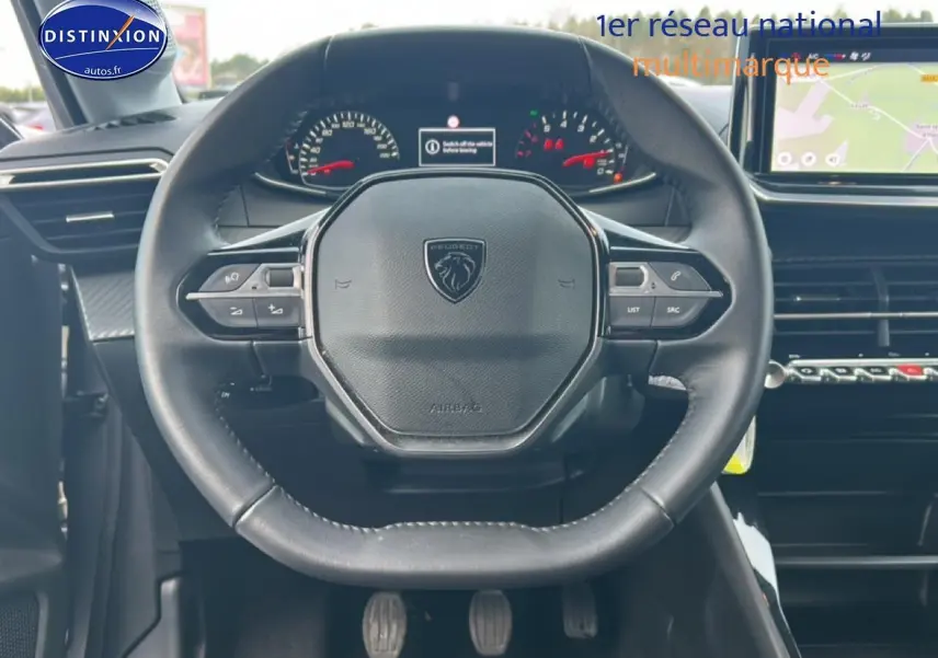 Vue centrée sur le volant cuir du Peugeot 208 1.2 100 style 2025 avec tableau de bord et écran tactile visibles.
