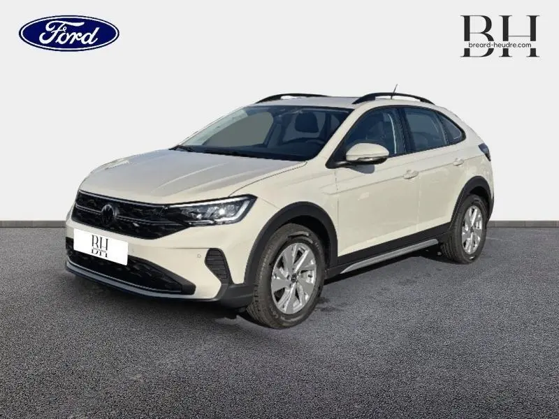 Vue 3/4 avant d'un Volkswagen Taigo blanc pur avec jantes alu et barres de toit noires sur fond neutre.