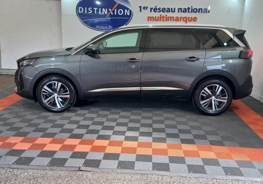 Profil droit d'un Peugeot 5008 gris foncé 2021 avec jantes alliage et toit contrasté blanc en intérieur showroom.