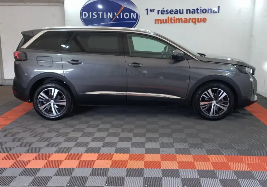 Profil droit d’un Peugeot 5008 gris foncé 2021 stationné en intérieur avec jantes alliage et vitres teintées.