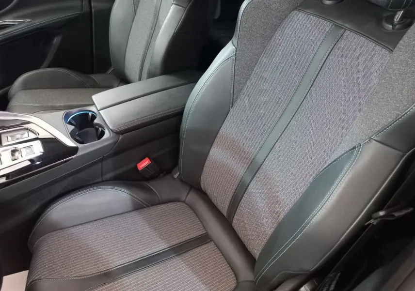 Gros plan sur les sièges avant gris foncé en tissu et cuir du Peugeot 5008 PureTech 130 Allure Pack, avec accoudoir central.