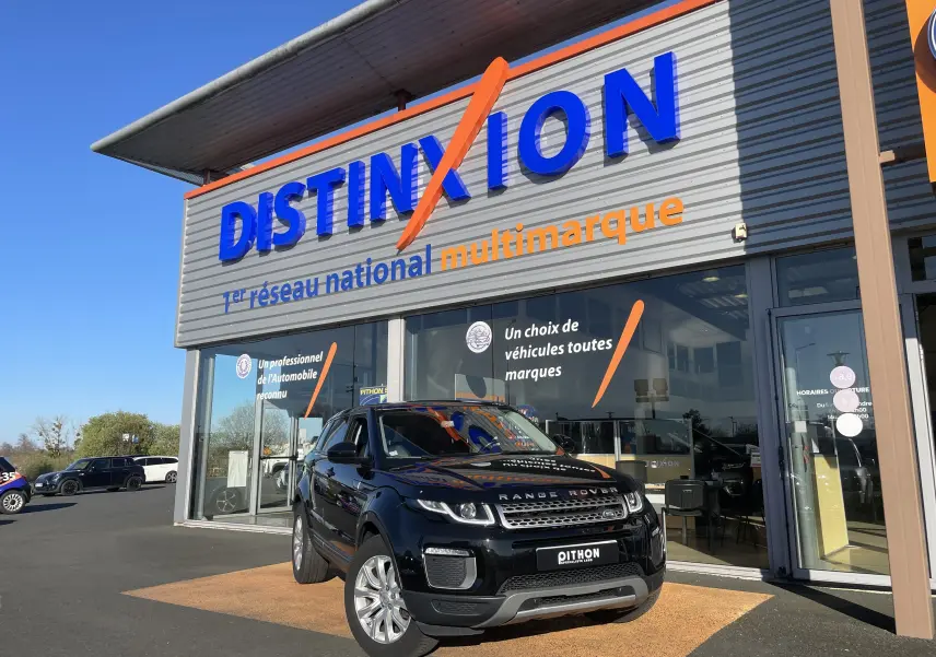 Range Rover Evoque noir en 3/4 avant droit devant un showroom avec enseigne Distinxion visible.