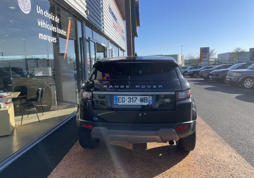 Vue arrière d'un Range Rover Evoque noir 2016 garé devant une vitrine, avec logo et plaque d'immatriculation visibles.