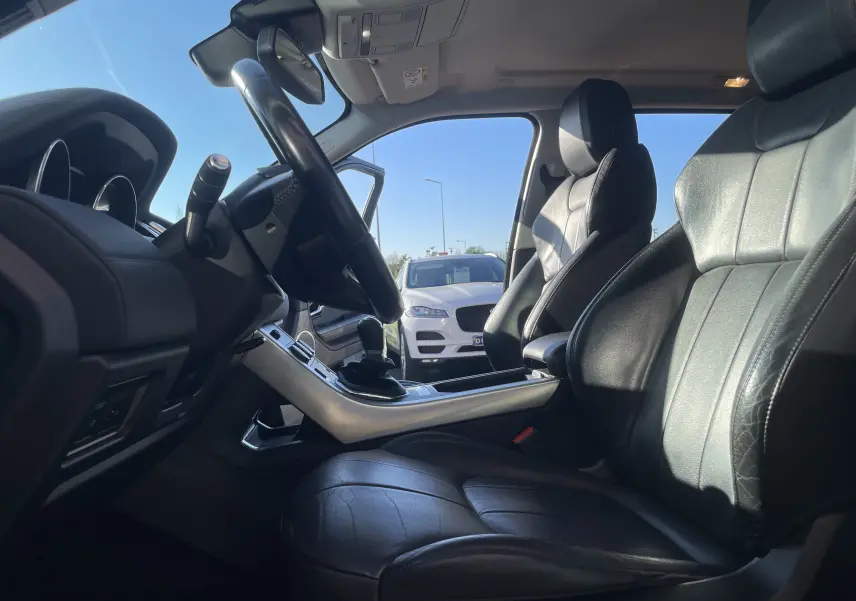 Vue intérieure côté conducteur du Range Rover Evoque noir 2016, avec sièges cuir noirs et volant multifonctions.