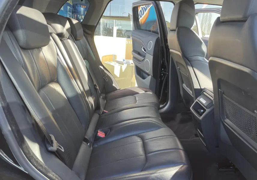 Vue intérieure arrière côté gauche du Range Rover Evoque 2016 noir, sièges cuir noirs et porte arrière ouverte.